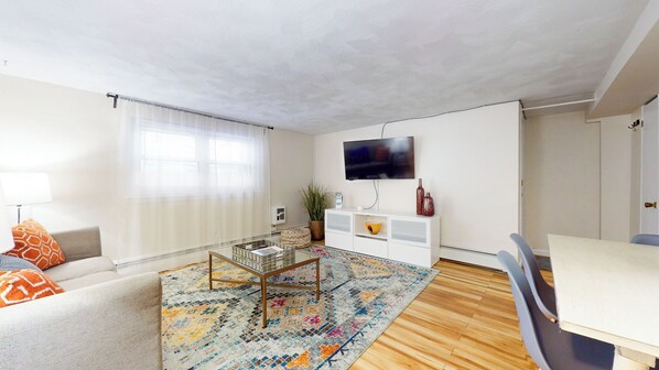 Bright and cozy living area featuring a stylish sectional sofa, a wall-mounted TV