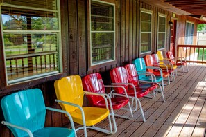 Chair lined covered porch in the country. Watch the hummingbirds & song birds