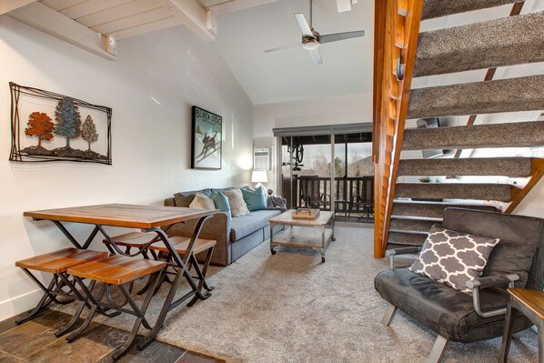 Cozy space with stairs, dining table, sofa bed, and patio view.