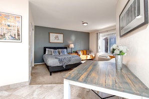 Cozy studio with queen bed, sofa, TV, and lovely window view.