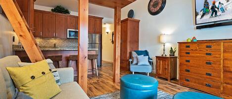 Cozy space with a sofa bed, TV, and kitchen bar stools.