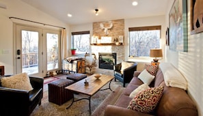 Living room with view of gas fireplace and entry with outside deck
