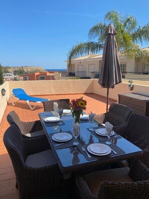 The outside alfresco dining area with a view of the pool terrace and the sea. 