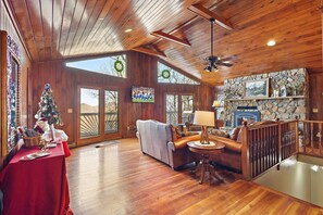 Main Living Area Features Large TV, Leather Seating, Floor to Ceiling Stone Fireplace, and Deck Access