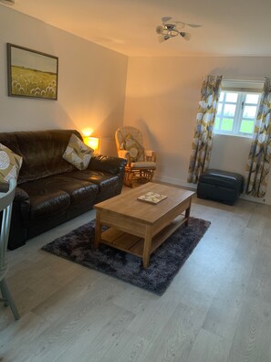 Lounge with 3 seater leather sofa and rocking chair, foot stall & coffee table.