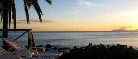 Relax on Shell Villa's oceanfront deck as the sun goes down over gently smoking Montserrat