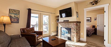 Open concept kitchen, dining and living area with gas fireplace, flat screen TV, pull-out sofa and views of the slope
