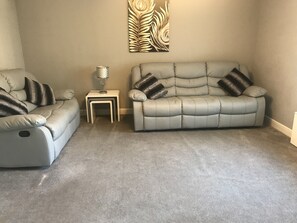 Spacious lounge with reclining sofas and wide screen smart TV