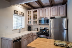 Efficiet kitchen is fully stocked with cooking utensils, coffee, tea and spices.