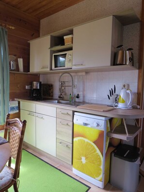 Moderne Küchenzeile mit Spülmaschine, Ceranfeld mit 2 Kochstellen, Toaster, Wasserkocher, Kaffeemaschine und Mikrowelle