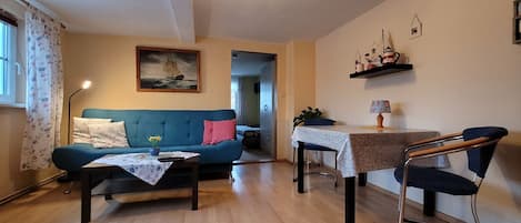 Wohnzimmer mit Flachbild-TV, Schlafcouch und Esstisch für 4 Personen