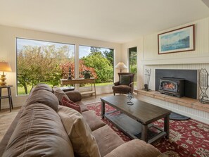 Open living room with large windows and cozy fireplace (firewood not provided)