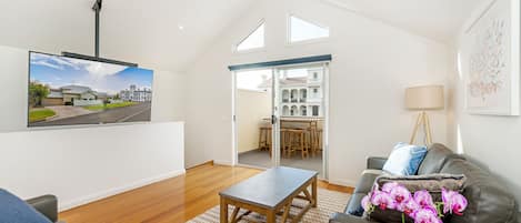 The large ceiling hung TV complements the airy feel to the living area