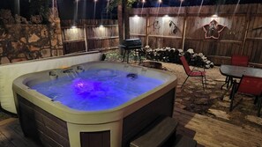 Alternate view of the hot tub and back yard with night lights and privacy fence.