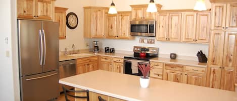 Kitchen with new stainless appliances, hickory cabinets and a breakfast bar.