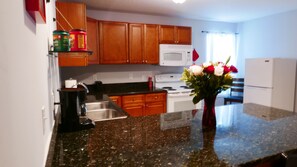 Kitchen with bar chairs, coffee maker, and coffee. 