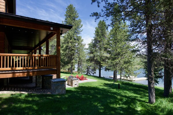 House with lake and yard including dock, firepit, and BBQ