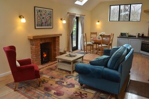 Well lit open plan living room with cosy wood burner.