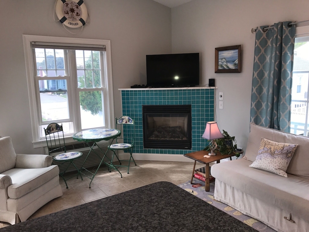 A turquoise fireplace is the focal point of a Westerly RI vacation rental with neutral couches and a coastal decor theme.