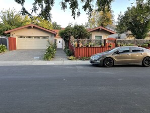 Street view of the house. Two cars can be parked in front of the patio fence. 