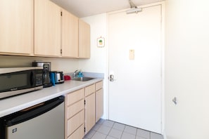 Kitchenette with mini fridge, 2 burners top, microwave and is equipped with coffee maker, toaster, dishes, silverware, and cooking utensils.