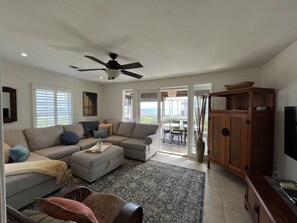 Living room with TV and entertainment center and dining area in the sunroom.