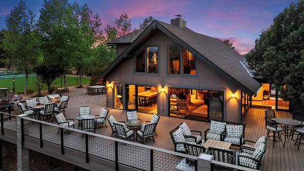 Spacious deck with seating, stunning forest views, and a nearby tennis court.