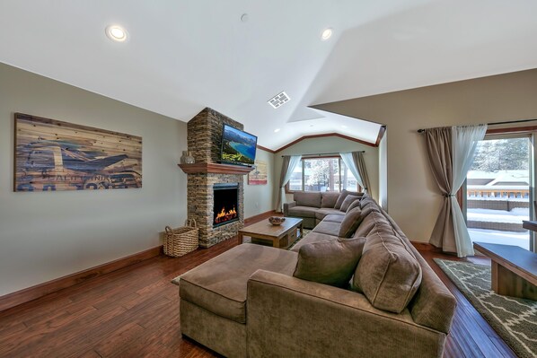 Living room with with sectional couch, 49” Samsung with Charter Cable, Yamaha sound bar, and gas fireplace (now with a brand new shuffleboard table!)
