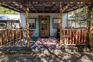 Covered front porch with table & chairs, and inviting wide benches for lounging