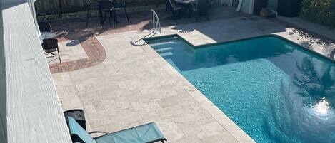 Pool deck has 7 lounge chairs and 13 chairs surrounding 3 tables. 