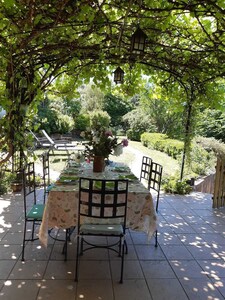 La belle terrasse sous la pergola  ombragée d'une vigne donnant sur la nature.