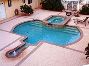 The pool with whirlpool and patio table, chairs and lounge chairs.