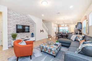 The living room, adorned with a plush couch, an accent chair and a sleek TV, offers a perfect blend of comfort and style. A welcoming oasis where relaxation meets entertainment, inviting you to unwind and indulge in moments of tranquility.