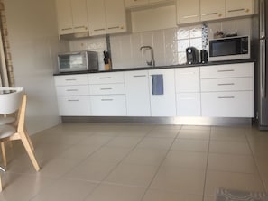 Kitchen with bench oven, double hot plate, fridge, microwave and coffee machine