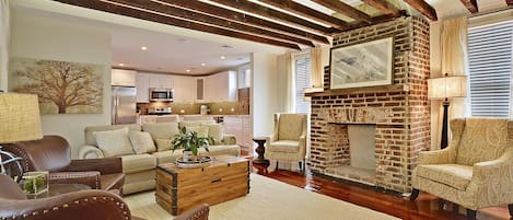 Living room featuring exposed beams, restored fireplace, and vaulted ceiling. 