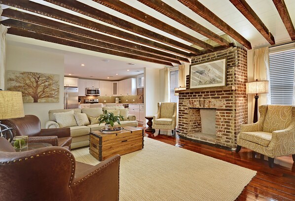 Living room featuring exposed beams, restored fireplace, and vaulted ceiling. 