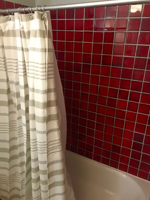 Updated bathroom features original dramatic red tile.