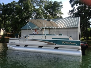 Pontoon boat parked in front of the boathouse and dock.