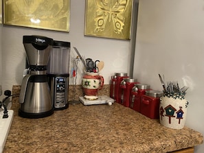 coffee station with utensils, coffee/flour/sugar canisters and phone charger