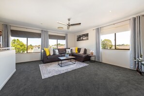 Spacious living area with leather sofa in a newly carpeted apartment. 