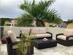 Third floor patio lounge furniture. Shade provided by large palm tree behind.