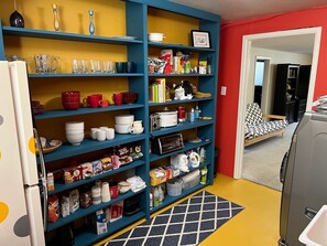 Kitchen open shelving. Well-stocked, full coffee bar, toaster oven, water jug.
