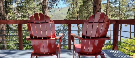 The deck boasts views of lake/mountains, charcoal BBQ, picnic table, and chairs.