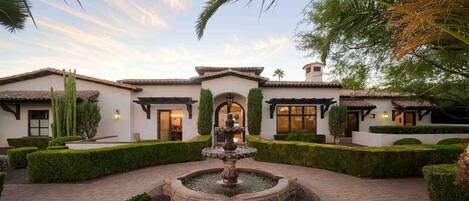 The front entrance features a beautiful water feature and manicured landscaping