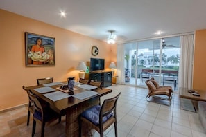 Large common area with dining table for six, flat-screen TV, and beautiful ocean mural