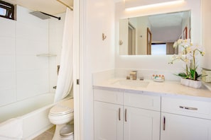 Bathroom with tub and shower combo. Sliding door separates the toilet and sink