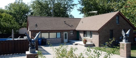 Front view of house, spacious cement driveway, and pool gate from Perryview Dr.