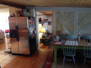 Stainless steel fridge and another room with table for working or playing