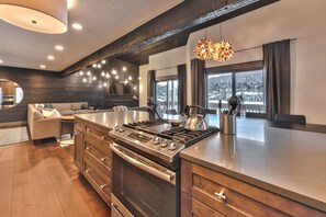 Fully-Equipped Kitchen with Stainless Steel Appliances, including a Gas Stove, Double Ovens, Quartz Countertops and Modern Decor