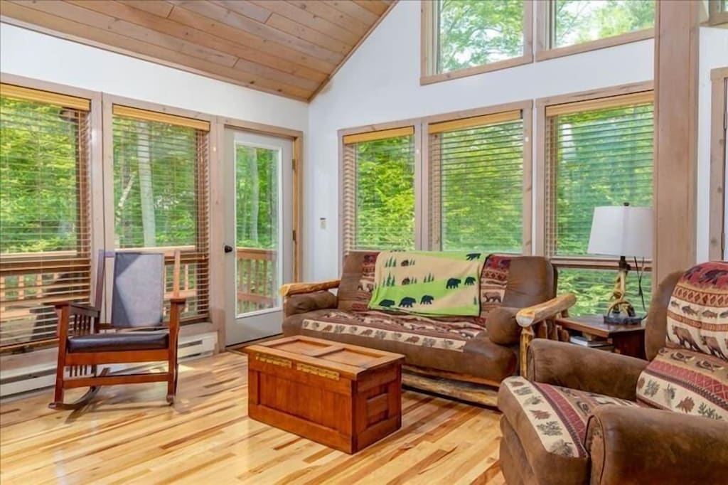 Living room with couches and chairs leading to deck, great view of trees out the window!